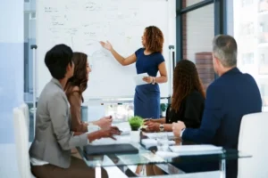 Profissional conduzindo treinamento corporativo para uma equipe em sala de reunião.
